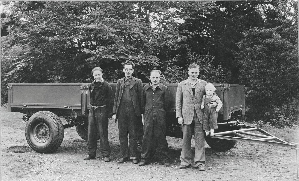 1947 - Anthony Bamford in his father's arm. From left are employees Bill Hirst, Arthur Harrison and Bert Holmes (1920).jpg